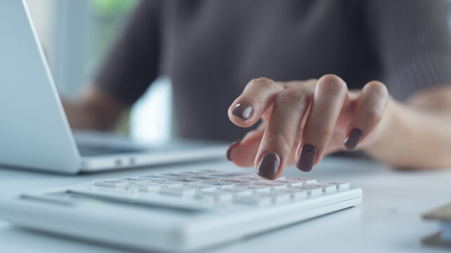 Business woman using calculator to calculate financial report, bookkeeping payroll and budget tax. Business, finance and investment, budget and tax calculation and planning - Powered by Adobe
