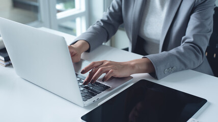 Close up of businesswoman working computer laptop searching or typing text message, surfing the internet, planning business project at office 