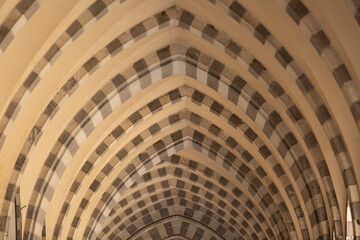 Fototapeta premium Looking through repetitive arches with pattern of dark and light coloured stones, Genoa