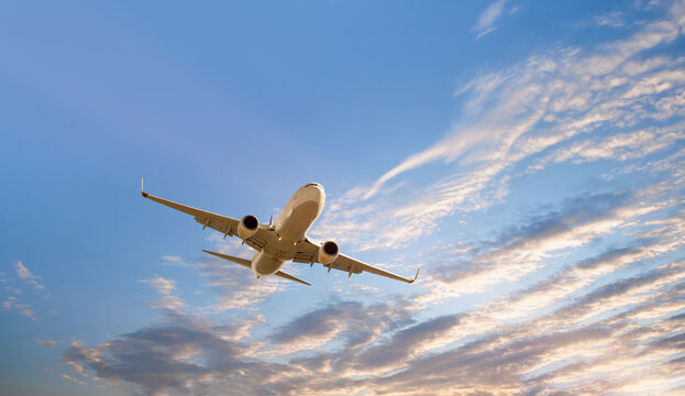 Fototapeta White passenger airplane flying in the sky amazing clouds in the background - Travel by air transport