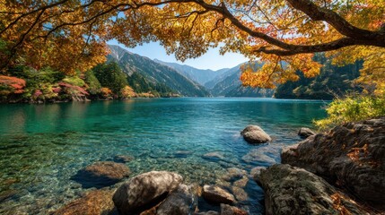 A serene lake with vibrant autumn foliage, surrounded by rocky shoreline and mountains in the distance.