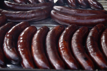 Many identical sausages on the grill, close-up. Cooking delicious sausage at a food festival. Sausage is very tasty with dark or light beer.