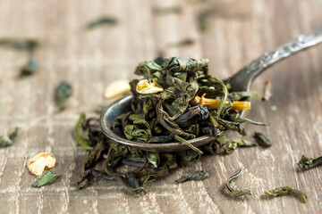 green tea leaves in a spoon on wooden background. a sample for package design