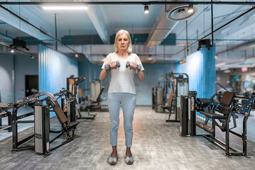 Senior Woman Lifting Dumbbells in Gym During Strength Training Session for Fitness Progress