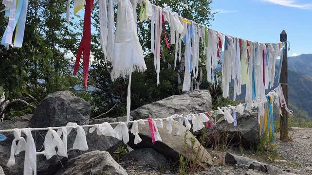 Video of Religious buddhist prayer flags in Altai Chike-taman mountain pass. Flags are flutter in the wind on blue sky and moutains on background.