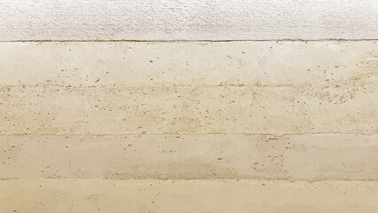 Close-up of a modern, eco-friendly rammed earth wall showcasing horizontal layers, natural warm tan...