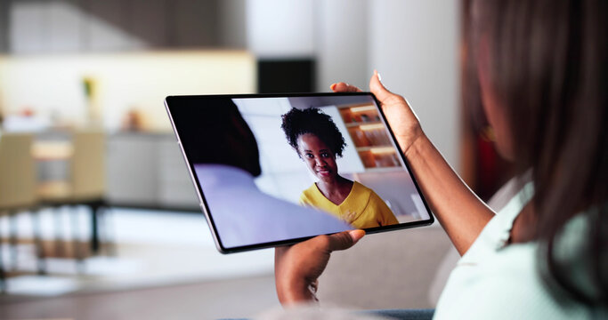Young African American Woman Streaming Video On Tablet In Living Room