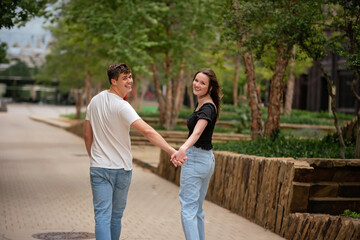Fototapeta premium Millenial Couple Hold Hands and Walk in Urban Park