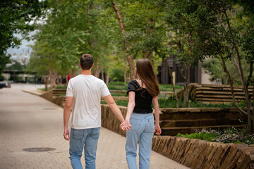 Fototapeta premium Young Faceless Couple Hold Hands Affectionately in City Park