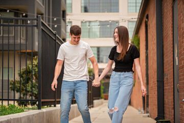 Obraz premium Laughing Couple Walks Playfully Holding Hands in Urban Area