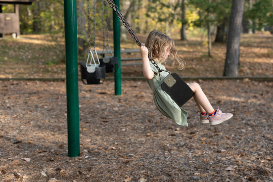 Young girl swinging at park on a sunny autumn afternoon.