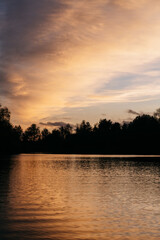 Golden sky and trees reflected in water at dusk
