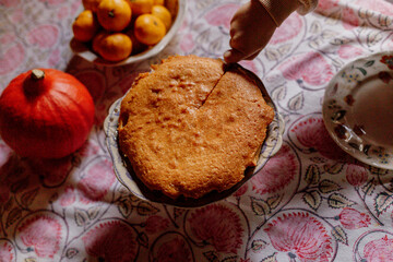 Child cutting homemade cake on patterned tablecloth