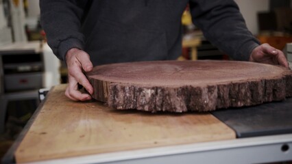 A craftsman carefully positions a thick, rustic wood slab in his.