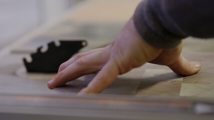 Skilled hand pushing wooden material towards a powerful saw blade