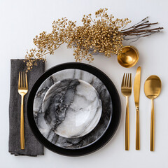 Elegant table setting with black and marble dinnerware accented by golden floral arrangements for a sophisticated dining experience.