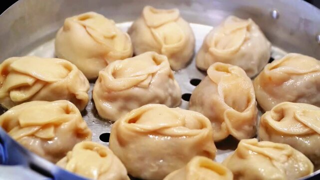 Delicious Manty, posture, khinkali is prepared in a special pot - mantoverde. Dishes of Asian, Buryat, Georgian cuisine. Aluminum steamer for cooking mantas on a stove in a home kitchen. Meat food.