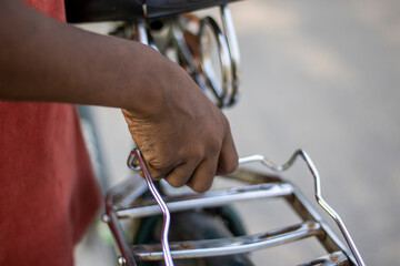 A persons hand is holding onto the metal rack of a scooter