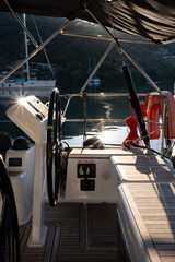 Peaceful sunrise view from a yacht cockpit with steering wheel and calm water, symbolizing freedom, adventure, and tranquil yacht travel.
