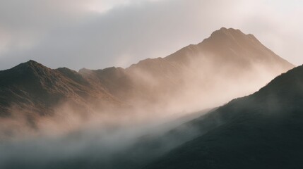 Fototapeta premium Landscape photograph of a mountain range. the mountains are covered in a thick layer of fog, creating a hazy and misty atmosphere.