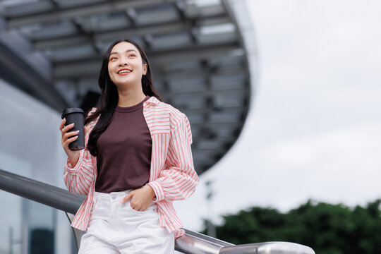 Young woman smiling holding coffee cup outdoors