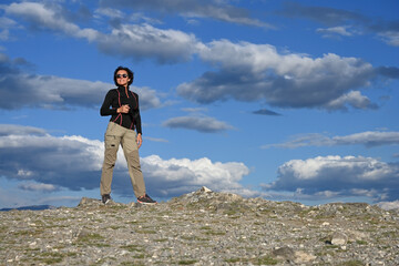 Middle-aged female tourist with a camera hiking in the mountains