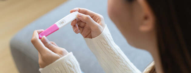 Close-up young woman checking on the pregnancy test and the result is positive. © Pormezz