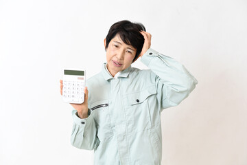 電卓を持ちながら困る作業服姿の中高年女性
