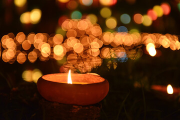 A candle flickers softly among glowing lanterns and colorful bokeh lights, capturing the warm spirit of Thailand’s Loi Krathong Festival night.