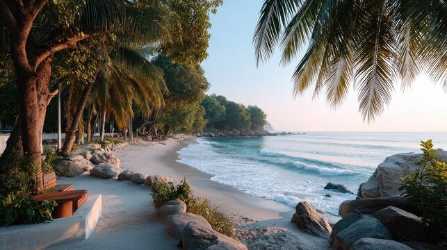 Backlit Photo Of Coconut Trees Swaying In The Breeze On A Serene Tropical Beach With Gentle Waves And Rocky Shoreline Under A Clear Blue Sky