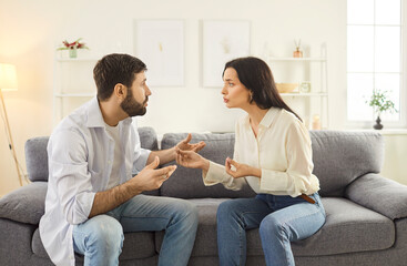 Angry couple conflict at home, young man, woman sitting on sofa in living room having family talk or quarrel in misunderstanding, husband and wife argument, relationships problems, breakup relations