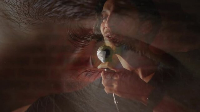 Male listener's eye filling view and reflecting singer bringing mic to lips singing performance