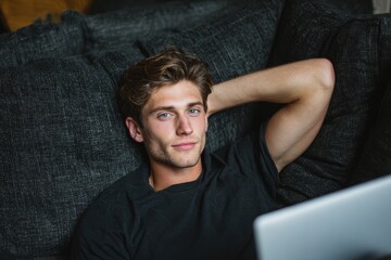 Obraz premium Young man lounging on a couch with a laptop