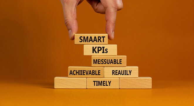 Hand arranging wooden blocks spelling SMARTKP Is SMART KPIs