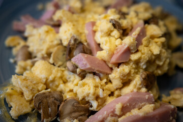Appetizing close-up of fluffy scrambled eggs with savory ham and fresh mushrooms. A perfect concept for a hearty breakfast or brunch, showcasing a delicious and high-protein meal.