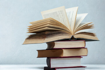 A stack of open and closed books on a white surface