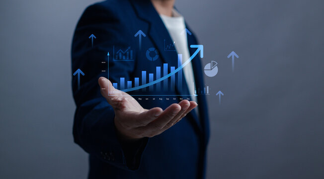 Businessman holding a growing bar chart with upward arrows, symbolizing financial growth, business success, data analytics, positive performance, marketing results and digital strategy - Powered by Adobe