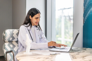 Dedicated female doctor analyzes test results on a laptop and document file while planning patient care solutions through telehealth. His focus reflects a commitment to healthcare excellence