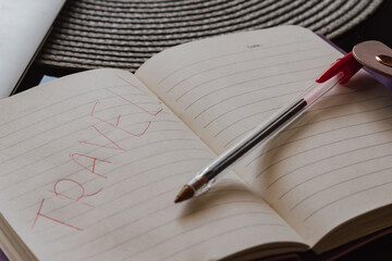 Handwritten red travel word on a notebook page with a pen, planning a trip