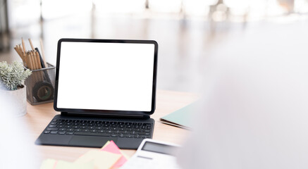 Fototapeta premium Close-up shot of a modern tablet with a blank white screen attached to a keyboard case, resting on a wooden desk in a bright office environment.