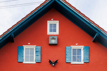 Striking red-painted farmhouse gable with blue window and a dragon as façade decoration