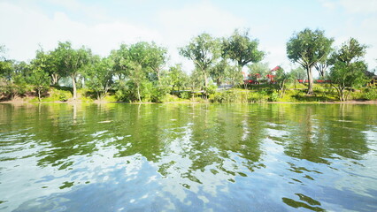 Calm waters reflect the vibrant trees along the shore, creating a serene atmosphere. This idyllic location invites exploration and relaxation on a sunny afternoon.