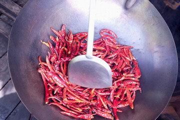 Putting the dried chilies in a pan, Thailand.