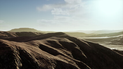 Soft hills stretch across the horizon, illuminated by the warm glow of the setting sun. The tranquil scene invites reflection and appreciation of natures beauty.