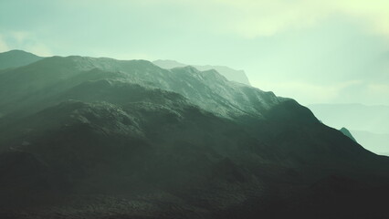 Mountains fill the scene with majestic peaks journeying into the mist. Soft sunlight touches the rugged terrain, creating an ethereal atmosphere, perfect for quiet contemplation.