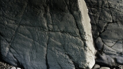 A rugged rock surface displays intricate textures and patterns shaped by time. The soft light highlights the details, revealing the beauty of natures artwork.