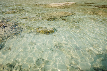 The sea water is crystal clear, you can see the coral reefs underwater and sunlight shimmers on the surface of water on Surin islands in National Park, Phang Nga of Thailand
