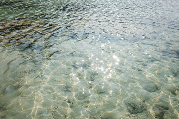 The sea water is crystal clear, you can see the coral reefs underwater and sunlight shimmers on the surface of water on Surin islands in National Park, Phang Nga of Thailand