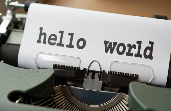 Vintage typewriter prints hello world on paper. Old mechanical device for writing text and communication. Nostalgic scene of classic letter typing on retro machine.