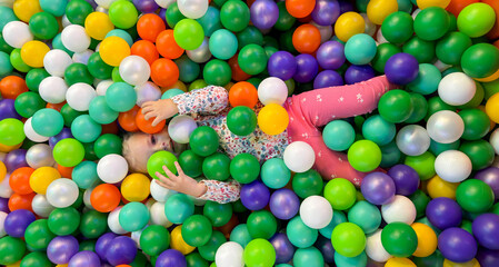 Happy Girl Playing and Lying in a Colorful Ball Pit Pool